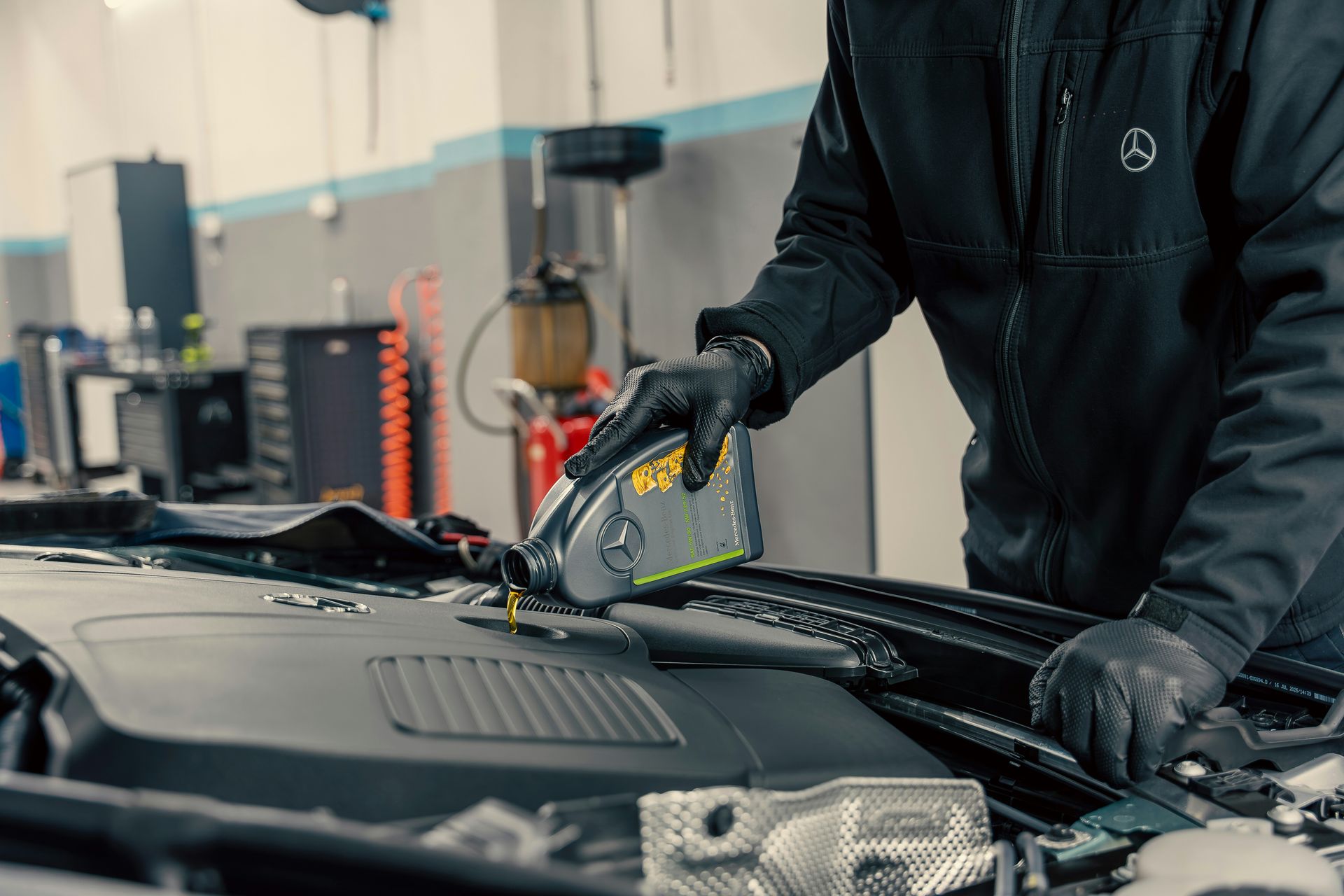 Mechanic pouring oil into car engine