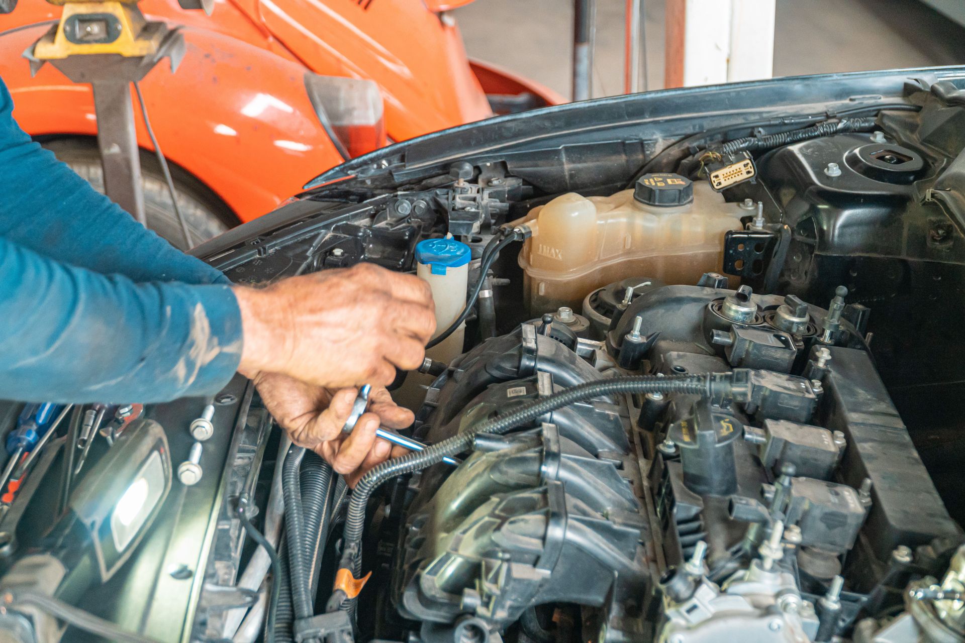 Mechanic's hands repairing a car engine, showing technical precision in an automotive garage.